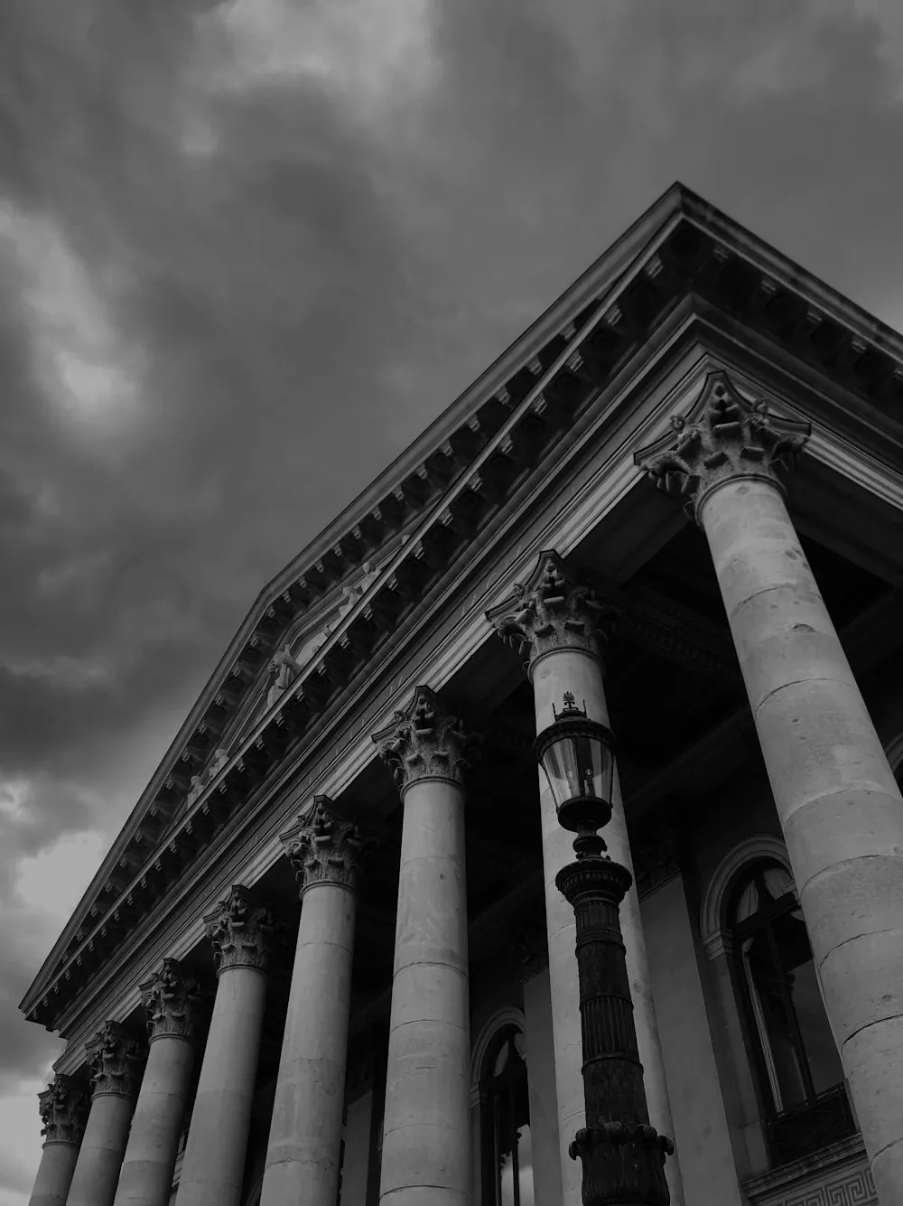 Stone columns and a pediment of a classical courthouse under heavy clouds