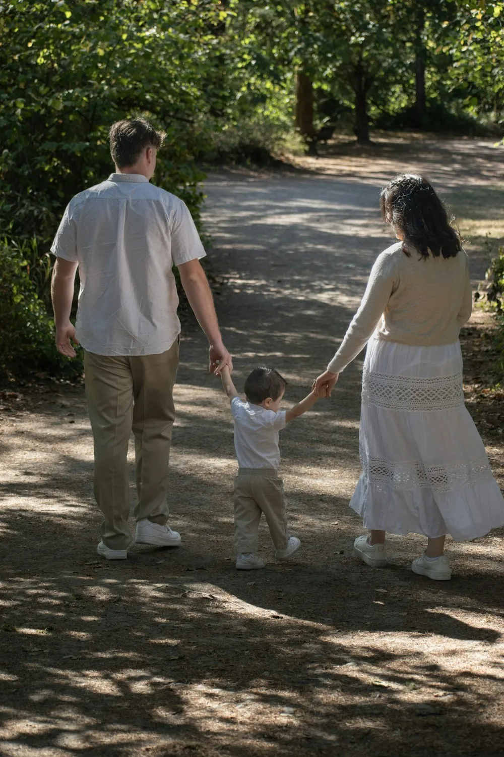 A family of three walking together along a wooded path